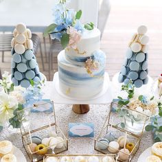 a wedding cake with blue and white flowers on top is surrounded by other desserts