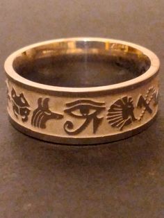 You are buying the Egyptian inspired ring pictured, it features a wonderful stainless  steel band with Egyptian symbols etched all the way around. This wonderful ancient Egyptian pattern inspired Ring will look amazing, very classic look, a great silver-tone accessory for that Egyptian look. Available in size 9  , these lovely rings are new old stock I got them from a costume jewelry warehouse that went out of business in the late 1990s. Please Note: These are comfort fit rings (rounded on the i Ancient Egyptian Jewelry Rings, Ancient Egyptian Accessories, Symbolic Silver Jewelry With Laser Engraving, Symbolic Silver Laser Engraved Jewelry, Symbolic Laser Engraved Silver Jewelry, Symbolic Nickel-free Engraved Ring, Silver Brass Jewelry With Engraving Option, Symbolic Carved Engraved Ring For Anniversary, Symbolic Engraved Ring For Promise