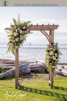 an outdoor wedding ceremony setup with flowers and greenery on the grass by the water