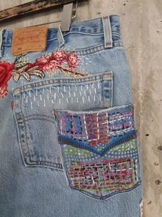 an old pair of jeans with embroidered flowers on them