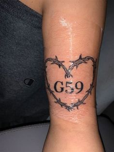 a heart with barbed wire and the number 59 tattoo on it's wrist is shown