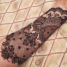 a woman's arm covered in hennap on top of a bed with intricate designs