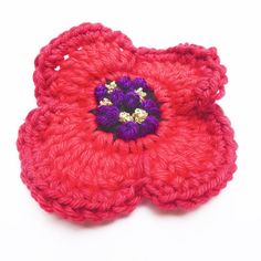 two crocheted red flowers with purple centers