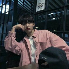 a man sitting at a table with a hat on his head and wearing a pink shirt