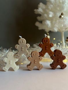 three gingerbread men are standing next to a white christmas tree