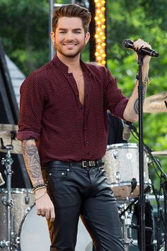 a man with tattoos on his arm holding a microphone in front of a drum set