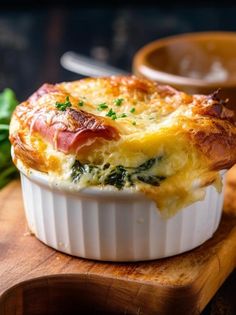 a casserole dish with ham and spinach in it on a wooden cutting board