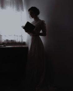 a woman standing in front of a window holding a book