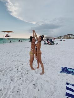 two women in bikinis standing on the beach