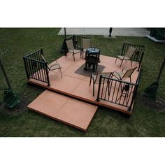 a patio with chairs and an umbrella in the grass next to a fire pit on top of some steps