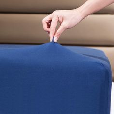 a person holding onto a blue piece of luggage with their hand on the top of it