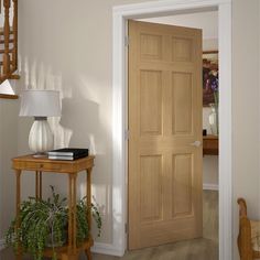 an entry way with a wooden door and potted plant on the table next to it