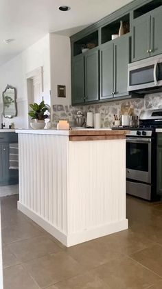 a kitchen with green cabinets and an island in front of the stove top oven is shown