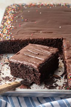 a chocolate cake with one slice cut out and sprinkles on the side