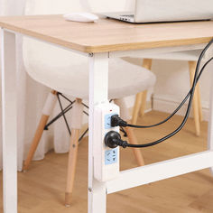 a laptop computer sitting on top of a wooden desk next to a white chair and table