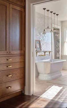 a bathroom with an old fashioned bathtub in the center and wooden cabinets on both sides