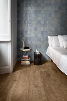 a bed sitting next to a nightstand on top of a wooden floor in a bedroom