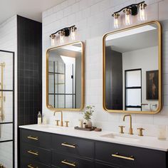 a bathroom with black and white tile, gold accents and two mirrors on the wall