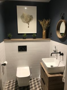 a white toilet sitting next to a bathroom sink under a framed art above the toilet