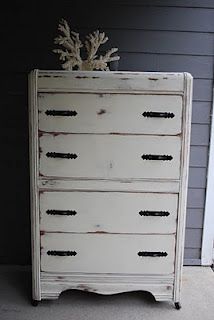 an old white dresser with some corals on it's top and bottom drawer