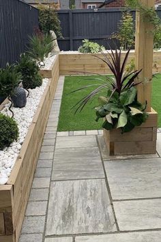 an outdoor patio with wooden planters filled with plants and rocks, along with grass