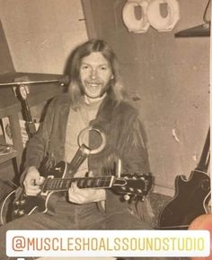 an old black and white photo of a man holding a guitar in front of him