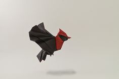 a black and red origami bird flying in the sky