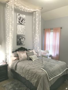 a bedroom with lights on the ceiling and a bed covered in grey sheets, pillows and blankets