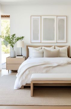 a bed with white linens and pillows in a bedroom next to two pictures on the wall