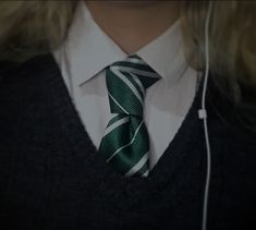 a woman wearing a green and white tie with headphones in her ears, looking to the side