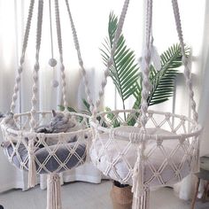 two hammocks hanging from the ceiling in a room with white walls and windows