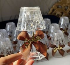 a hand is holding up a clear glass candle holder with a bow on the top