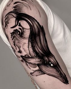 a black and white photo of a man's arm with a whale tattoo on it