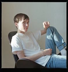 a young man sitting in a chair with his legs crossed