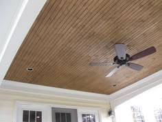 a ceiling fan mounted to the side of a wooden ceiling in a room with white doors and windows