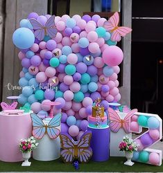 there are many balloons and decorations on the ground outside in front of a building that is decorated with butterflies