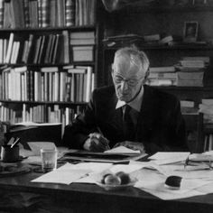 an old man sitting at a desk in front of books