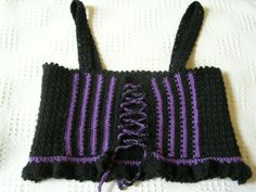 a crocheted black and purple top with ruffles on the bottom, sitting on a white surface