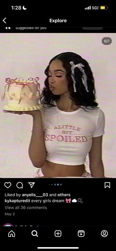 a woman holding a cake in front of her face while wearing a white shirt and black pants