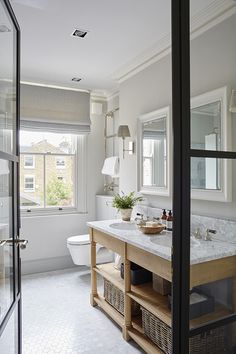 a bathroom with two sinks and a large mirror in it's center window, next to a toilet