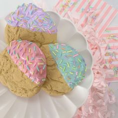 three cookies with frosting and sprinkles on a plate