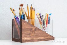 a wooden pen holder with pens and pencils in it