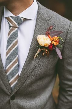 a man wearing a suit and tie with a boutonniere on his lapel