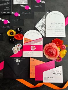 the wedding stationery is laid out on top of the black and pink table cloth