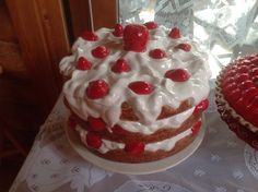 two cakes with white frosting and red cherries on top sitting on a table