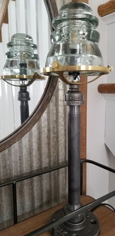 an old fashioned table lamp sitting on top of a wooden table next to a mirror