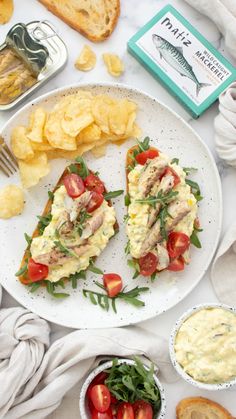 an open faced sandwich on a plate with chips and tomatoes