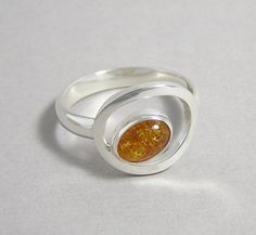 Amber and Sterling Silver Orbit Ring Modern Orange Oval Rings, Modern Amber Oval Ring, Modern Oval Amber Jewelry, Modern Amber Oval Jewelry, Modern Amber Rings For Anniversary, Modern Sterling Silver Oval Cabochon Ring, Modern Sterling Silver Ring With Oval Cabochon, Modern Sterling Silver Rings With Oval Cabochon, Amber Sterling Silver Oval Cabochon Ring