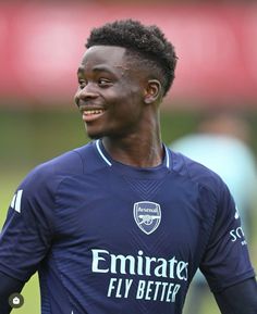 a soccer player is smiling and looking to his left with the ball in his hand