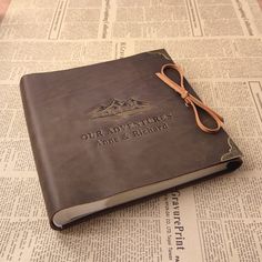 an old leather book with the words our adventures are here written on it and tied up